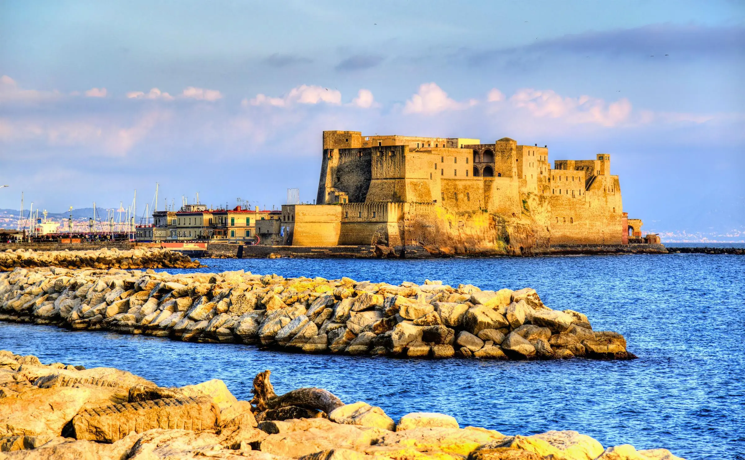 The stone walls of Castel dell'Ovo rising from the Gulf of Naples at sunset